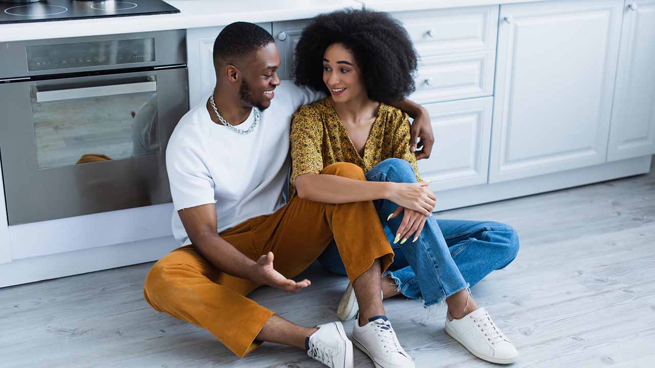 Couple sitting on kitchen floor discussing life.