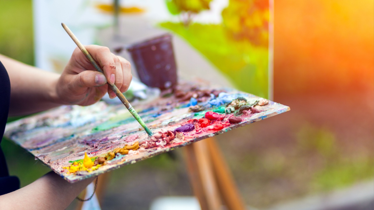 a hand holding a paintbrush and palette.