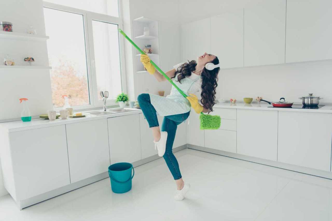 happy woman using broom dancing and having fun while cleaning.