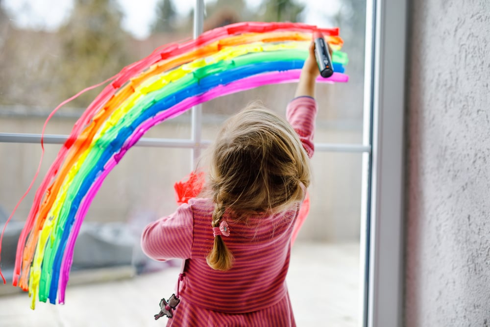 toddler painting rainbow on a window