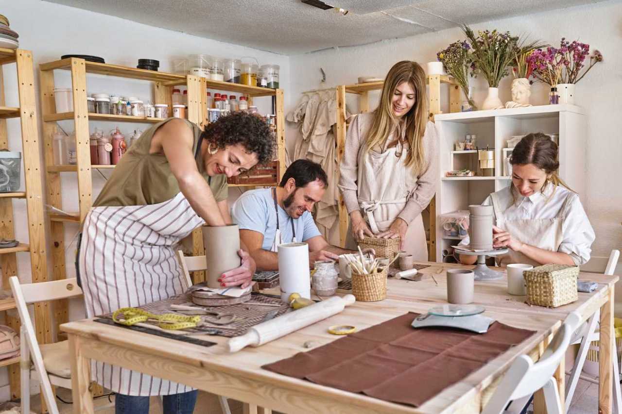 Four people engaging in pottery making in a workshop.